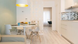 Cozinha moderna com armários brancos, área de jantar com mesa e cadeiras redondas, e divisória decorativa com desenhos recortados.