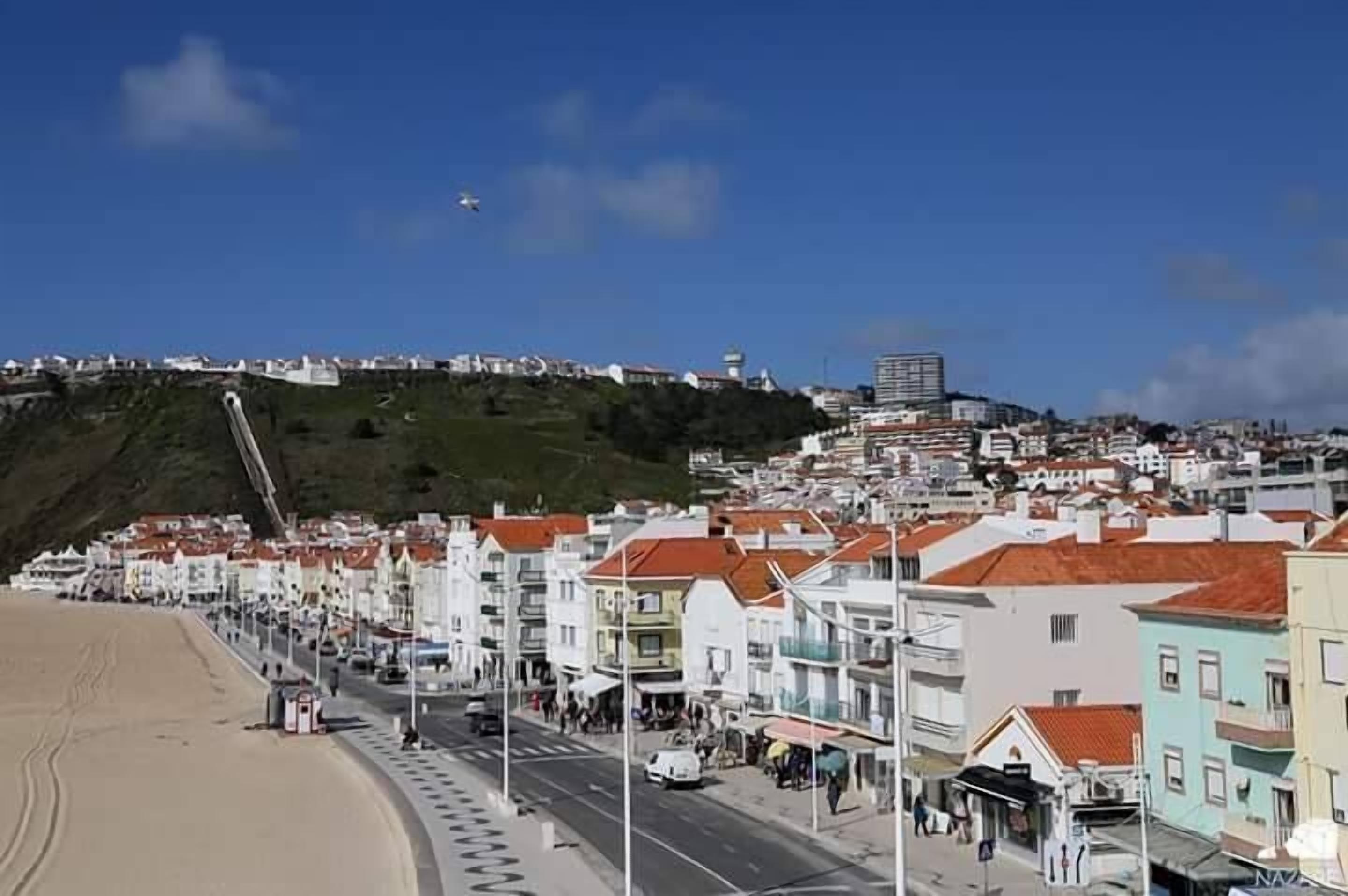 Eine Küstenstadt mit einem markanten Hügel, einem Strand und einer Mischung aus traditionellen und modernen Gebäuden.