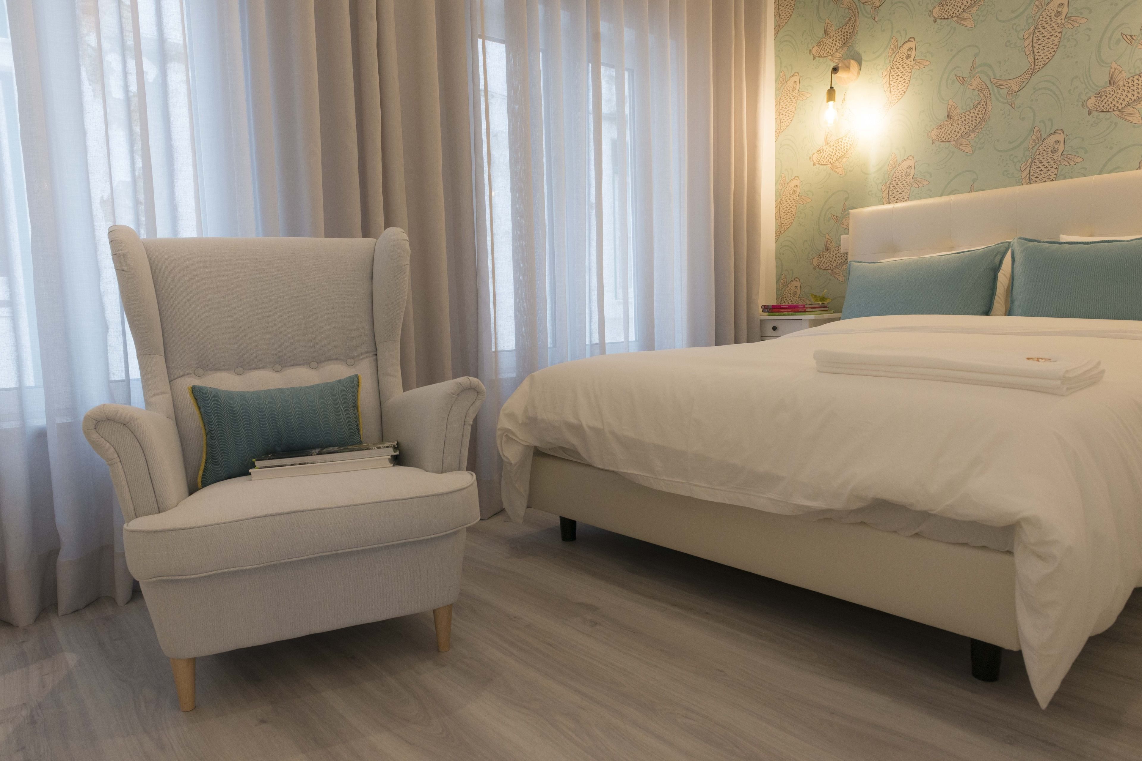 Een hotelkamer met een bed, een stoel en een nachtkastje.