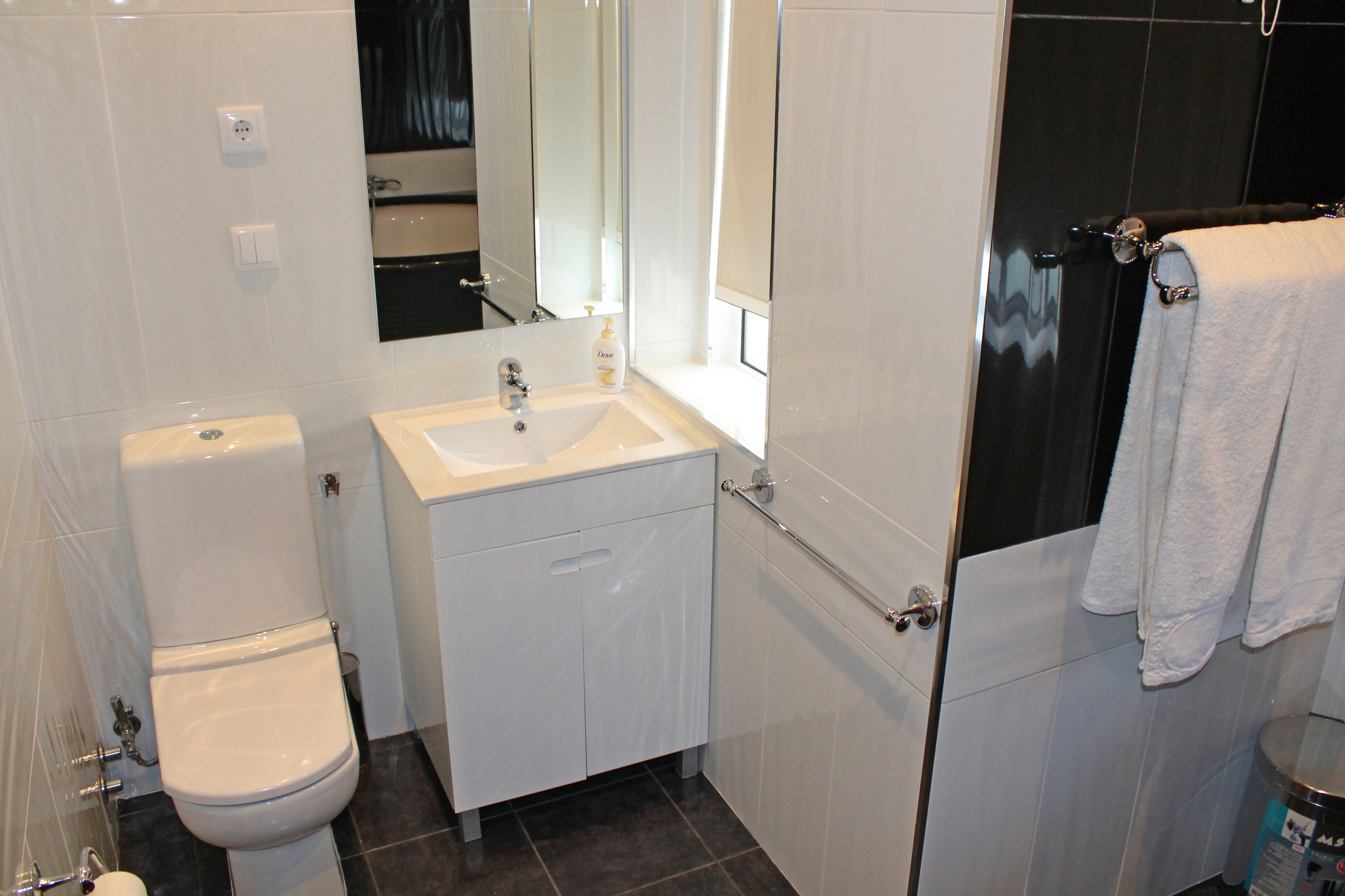 Un bagno moderno con il water, lavandino e specchio.