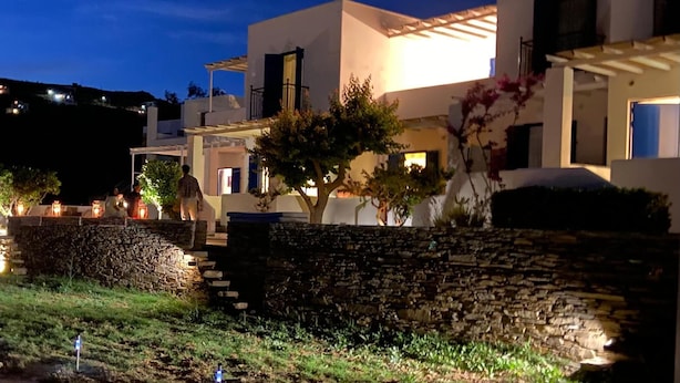 Un edificio moderno con un muro de piedra y un árbol en primer plano.