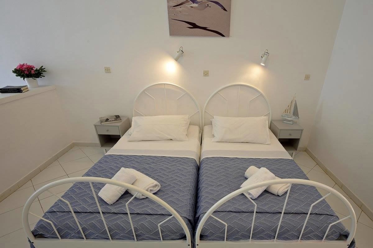 Habitación doble con dos camas, cada una con cabecera, mesita de noche y lámpara.