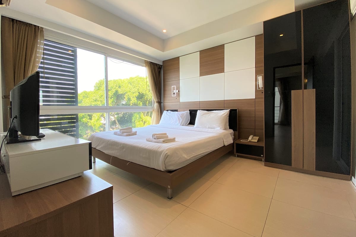 A modern hotel room with a bed, bedside table, and a desk with a computer.