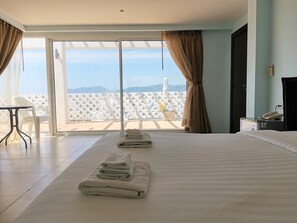 A hotel room with a large bed, a desk, and a view of the cityscape through the balcony. - I Am Residence (Patong)