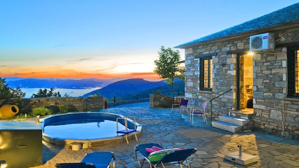 A stone building with a pool, outdoor seating, and a view of the mountains. - Pelion Goddess Villas (Volos)