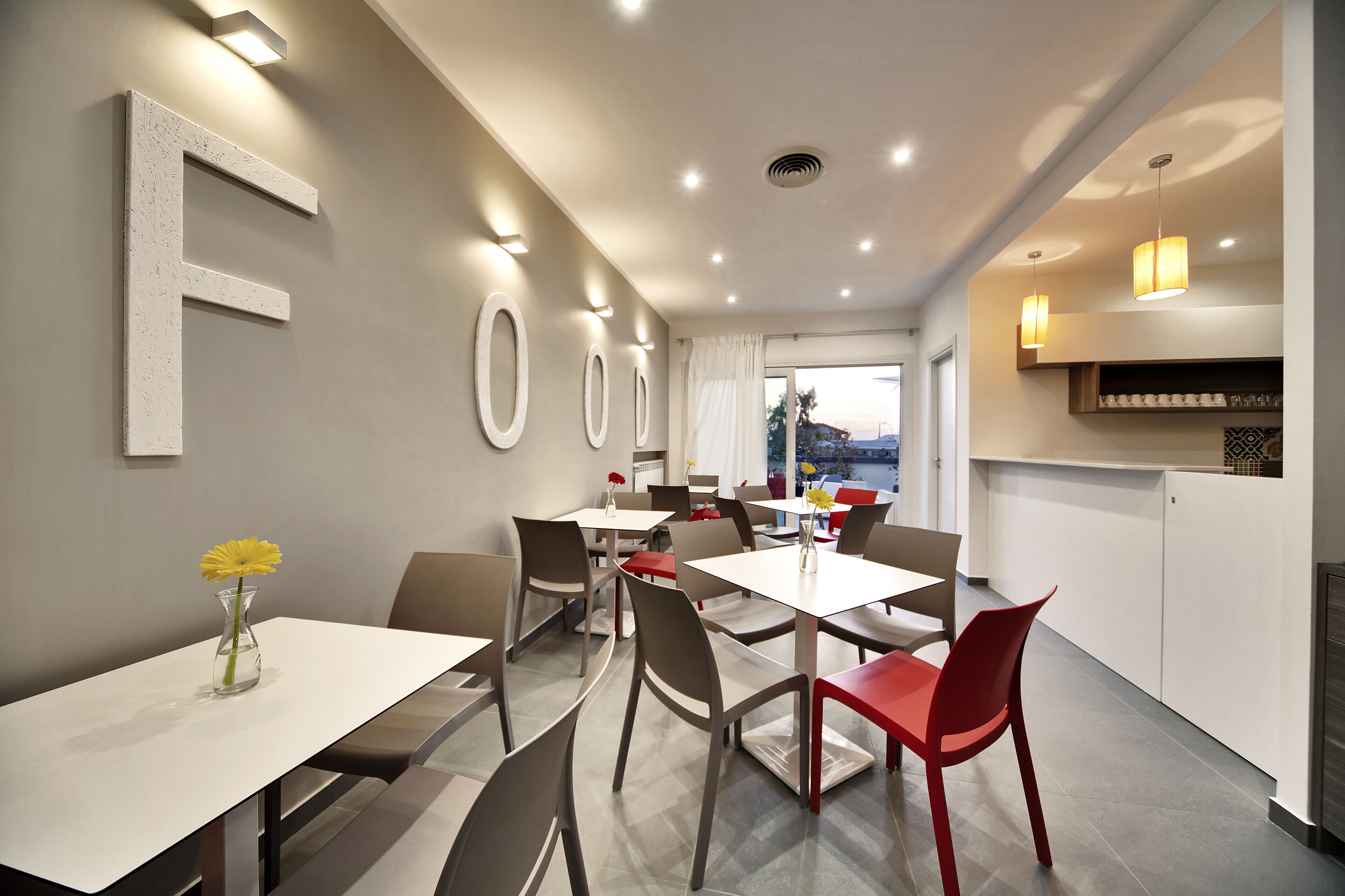 Een moderne eetruimte met een grote 'F' op de muur, meerdere tafels en stoelen.