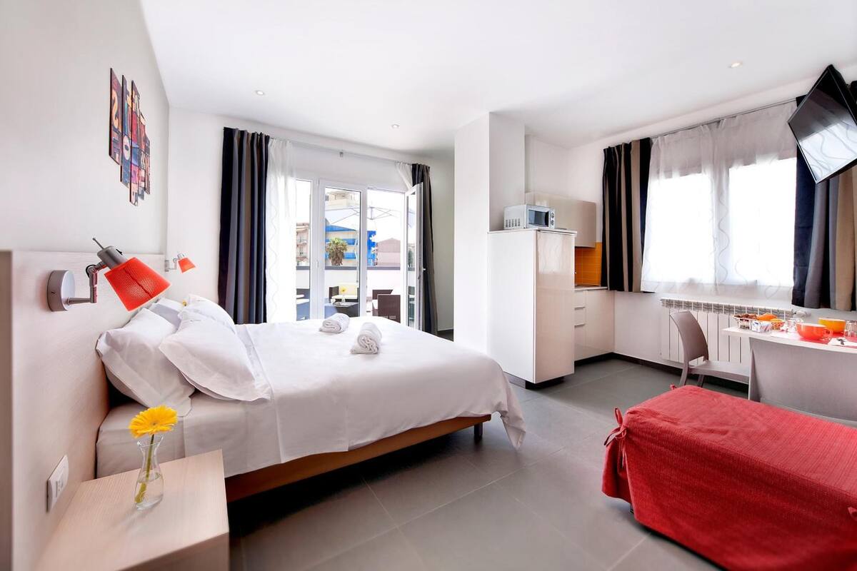 Ein modernes Hotelzimmer mit einem Bett, einem Nachttisch und einem Schreibtisch mit Stuhl.
