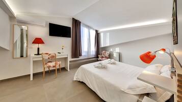 A hotel room with a bed, desk, chair, TV, and a window with curtains.
