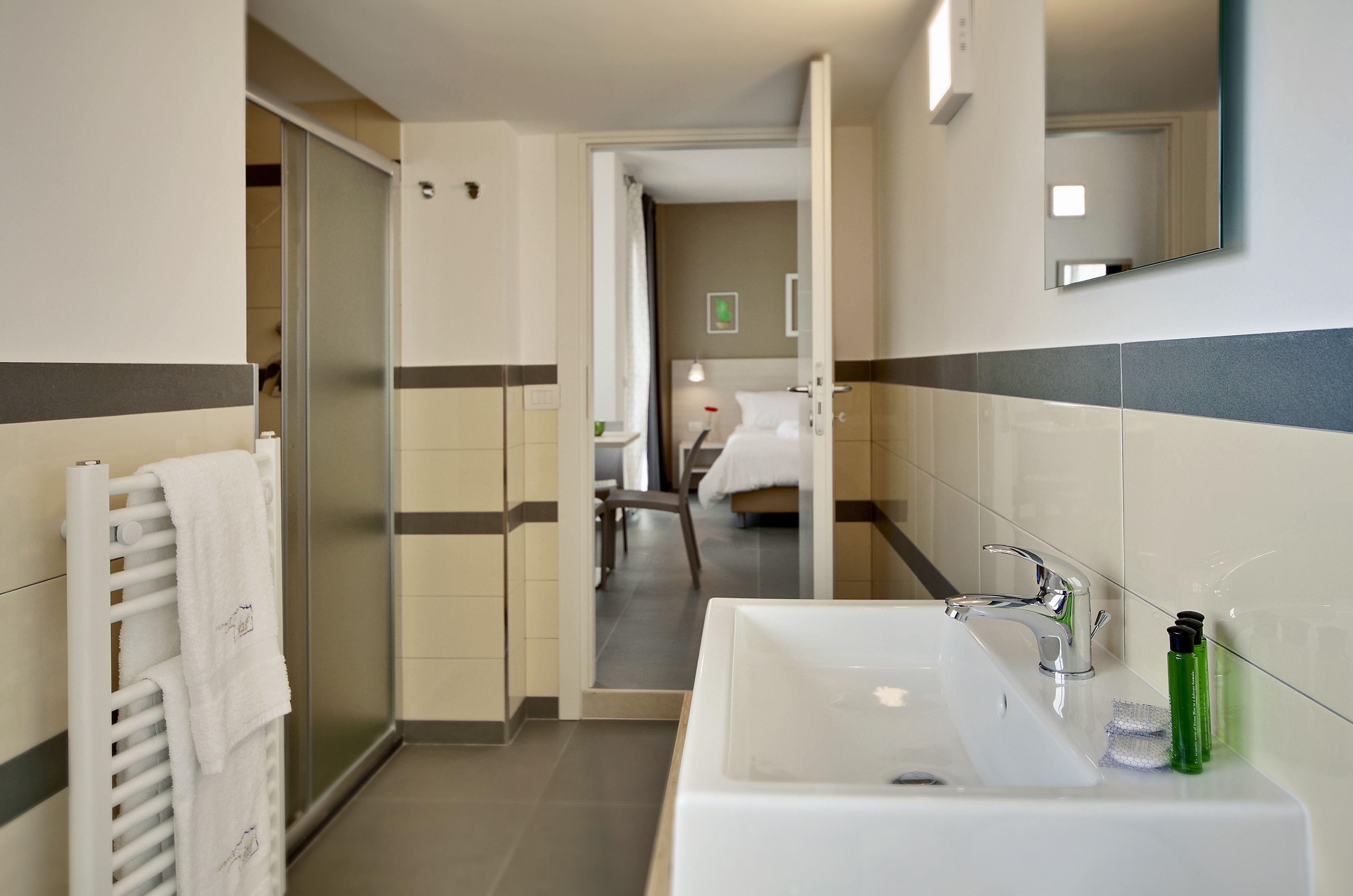 A modern hotel bathroom with a white sink, a mirror, and a towel rack.
