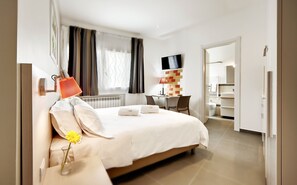 A hotel room with a bed, a desk, a TV, and a bathroom visible through an open door. - Residence Dei Viali (Ragusa)