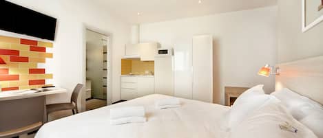 Una habitación de hotel moderna con una cama bien hecha, un escritorio y una zona de ducha.