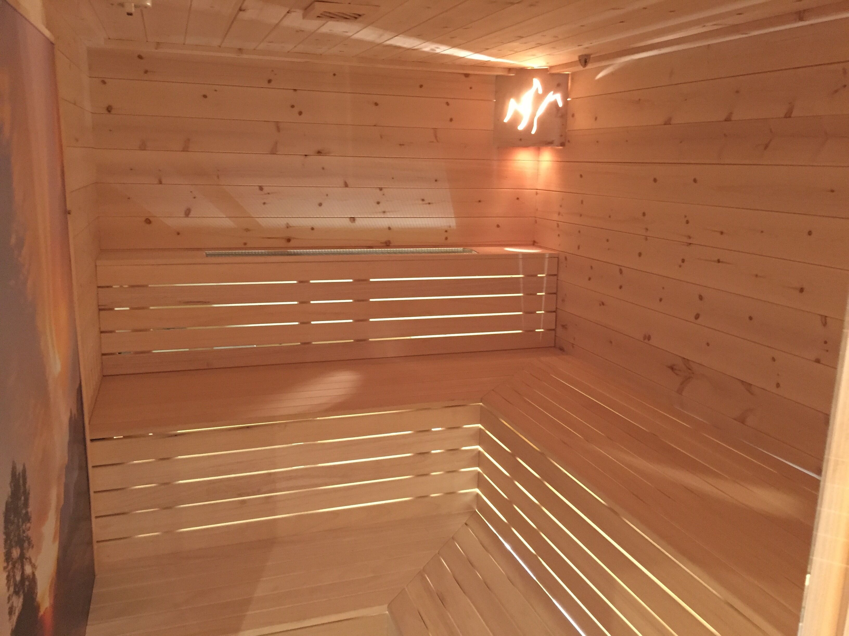 A sauna with wooden walls and benches, a ceiling with a light fixture, and a small window.