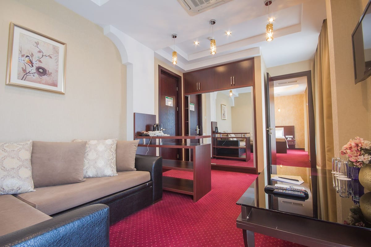 Een hotelkamer met een bank, een bureau, een bed en een rood tapijt.