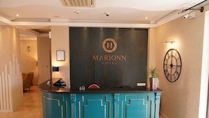 En receptionsdisk i en färgskala med nyanser av turkos, med Marionn Hotels logotyp.
