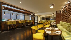 A modern restaurant with yellow chairs, a bar area, and a brick wall. - La Marvella, Bengaluru (Bengaluru)