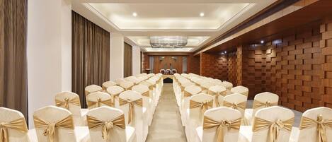 A conference room with rows of chairs, a podium, and a wooden wall panel.