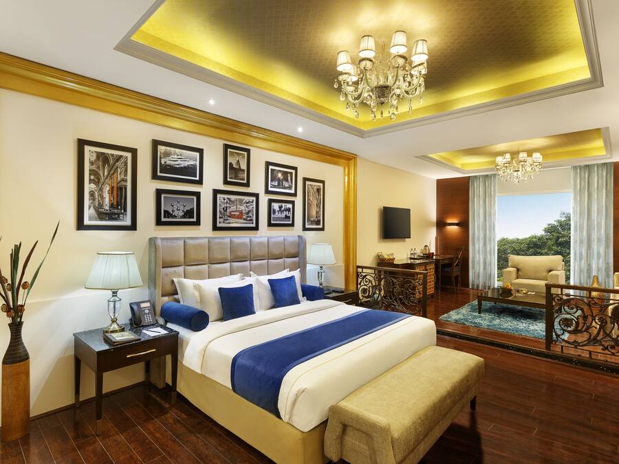 A spacious bedroom with a large bed, bedside tables, a desk, and a balcony with a view.
