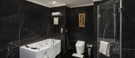 A luxurious bathroom with a freestanding bathtub, a glass-enclosed shower, and marble walls.