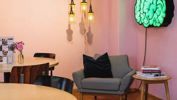 Um quarto aconchegante com uma mesa de jantar de madeira, um sofá xadrez e um luminária em formato de cérebro fixada na parede.