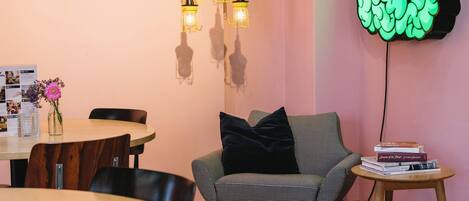 A cozy room with a wooden dining table, a checkered sofa, and a wall-mounted brain-shaped light fixture.