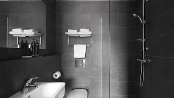 Une salle de bain moderne avec un lavabo blanc, des toilettes, une douche en verre et des porte-serviettes.