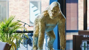 A gorilla statue on a pedestal in a room with a brick wall and large windows. - The Social Hub Groningen (Groningen)