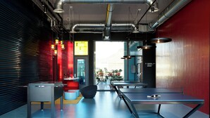 A modern indoor space with a foosball table, a ping pong table, and a seating area with a red and white color scheme. - The Social Hub Groningen (Groningen)