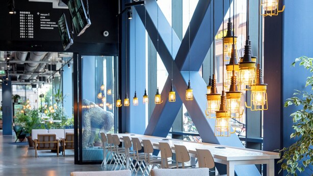 A modern interior with seating arrangements, a table, and hanging lights. - The Social Hub Groningen (Groningen)