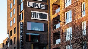 En bygning med flere etager, med et skilt der står: "EVERY BODY SHOULD LIKE EVERYBODY".