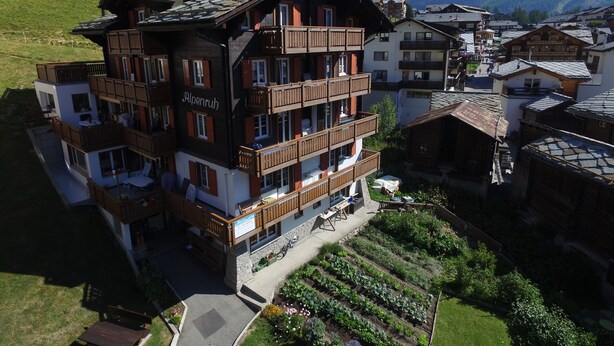 A multi-story hotel with balconies, a garden area, and a view of mountains. - Chalet Alpenruh (Saas-Fee)