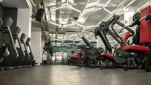 Uma academia com equipamentos de ginástica, incluindo esteiras e máquinas de peso, e um teto com iluminação geométrica.
