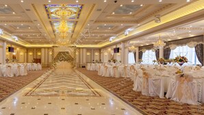 Uma sala de baile imponente com um corredor central, lustres ornamentados e arranjos florais.