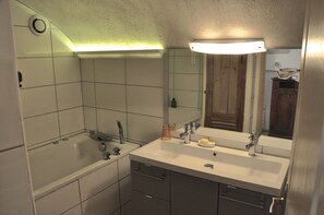 Ein Badezimmer mit einer Badewanne, einem Doppelwaschbecken und einem Spiegel.