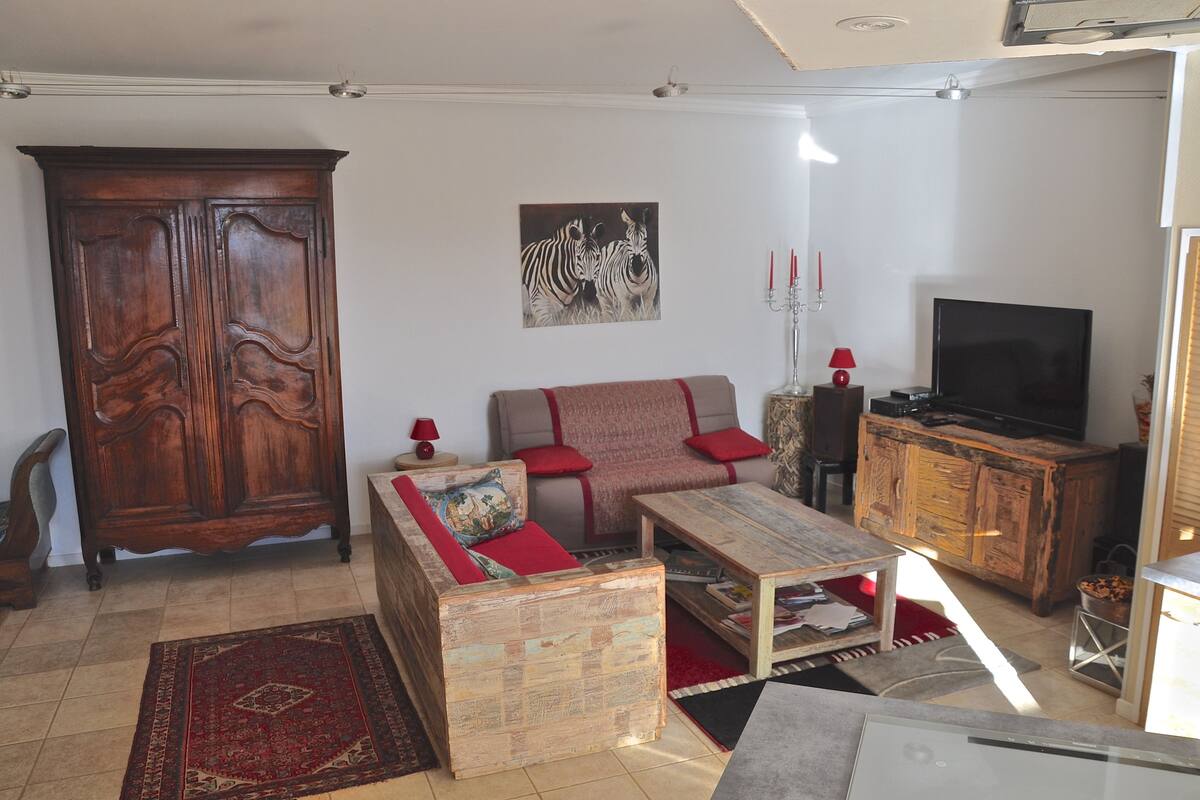 A living room with a wooden cabinet, a sofa, a coffee table, a television, and a red rug.