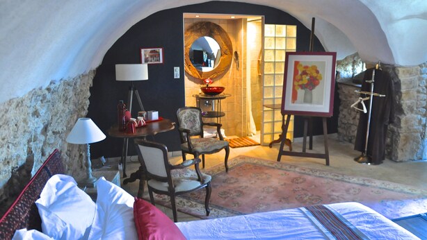 A cozy room with a bed, a desk, a chair, a round mirror, and a painting on the wall. - Le Clos du Cher en Beaujolais (Saint-Germain-Nuelles)