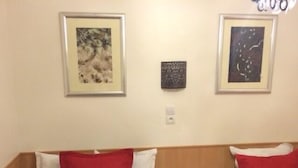 A hotel room with two beds, each with a red and white pillow, and a wooden headboard. There are framed artworks on the walls. - Hôtel Nice Savoie (Nice)