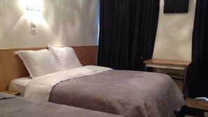 A hotel room with two beds, a nightstand, a lamp, and a TV on the wall. - Hôtel Nice Savoie (Nice)
