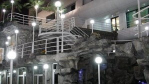 A multi-level hotel with a modern design, featuring a prominent staircase and a rocky facade. - Cruise Hotel (Tbilisi)