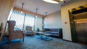 A modern lobby with a seating area, a coffee table, and a large window with a geometric pattern. - Cruise Hotel (Tbilisi)