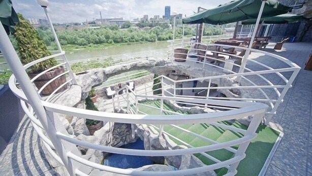 A circular outdoor seating area with a view of a river and city skyline. - Cruise Hotel (Tbilisi)