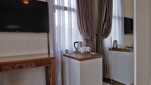 A hotel room with a wooden desk, a flat-screen TV, a small table with a kettle, and a mirror cabinet. - Arart Hotel (Istanbul)