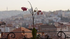 A balcony with a potted orchid, two chairs, and a cityscape view in the background. - Arart Hotel (Istanbul)