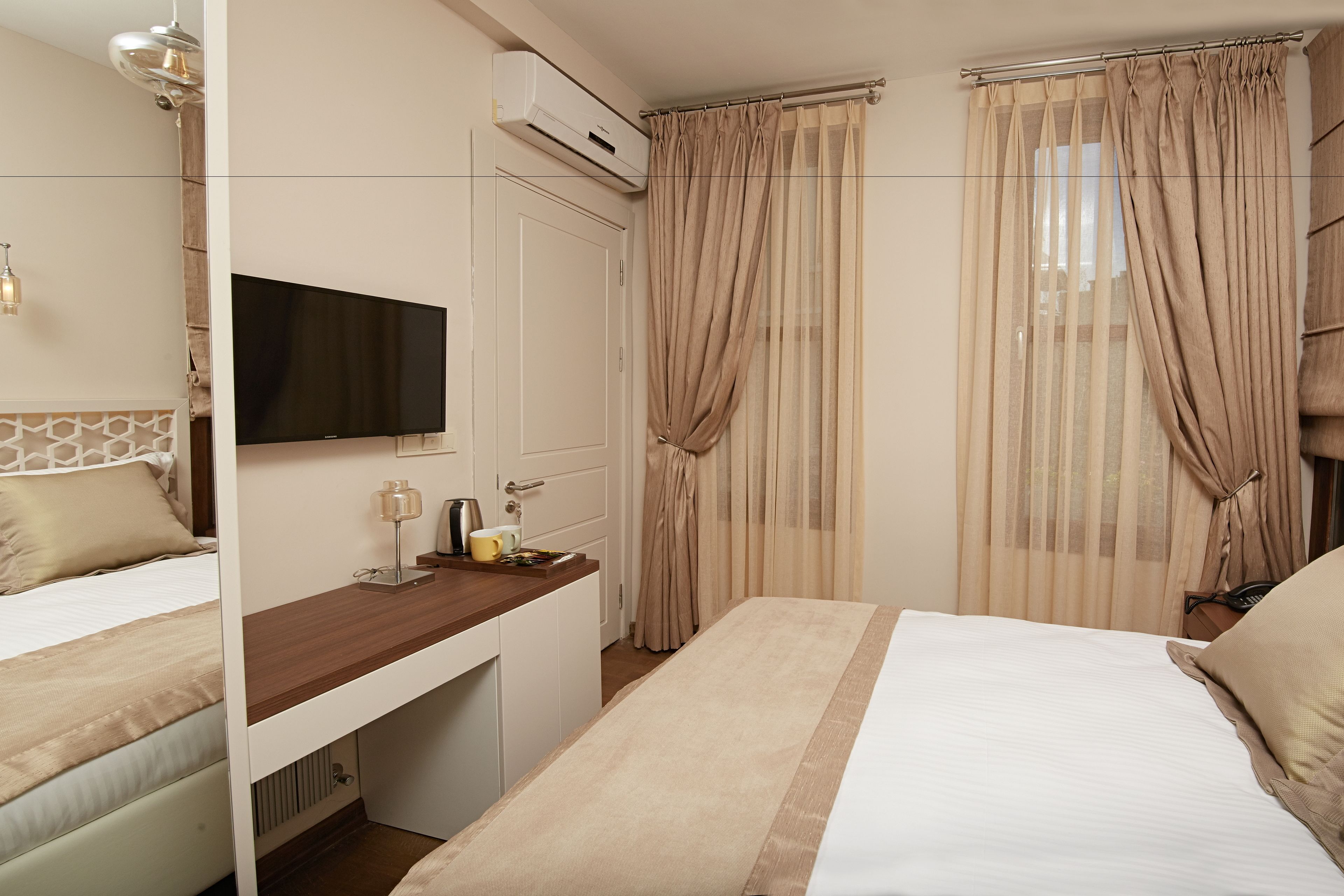 A hotel room with a bed, a desk, a TV, and curtains.