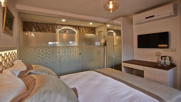 A modern hotel room with a large bed, a TV, a minibar, and a glass partition wall. - Arart Hotel (Istanbul)