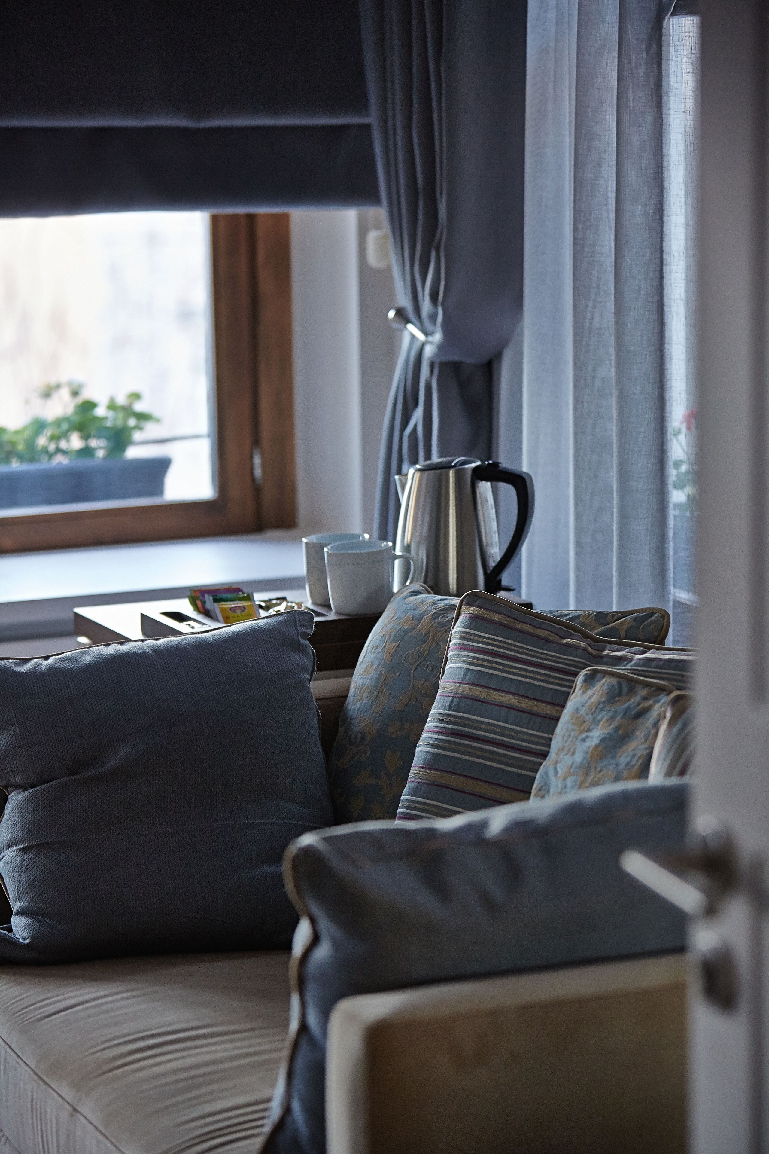 Una sala de estar moderna con sofá, cojines, una mesita de centro y una ventana con cortinas.