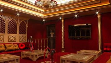 Una habitación lujosa con alfombra roja, techo ornamentado y mobiliario tradicional.