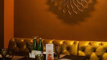 A dining area with a chandelier, a wall-mounted decorative light, and a table set for two with a menu.