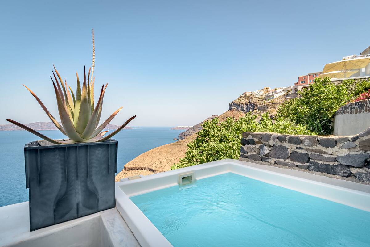 A pool with a clear view of the sea and a stone wall.