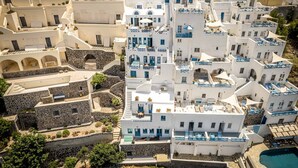 Un bâtiment blanc agrémenté de touches de bleu, un mur en pierre et une piscine.