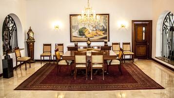 Un comedor elegante con una araña, un cuadro grande y un piso pulido.